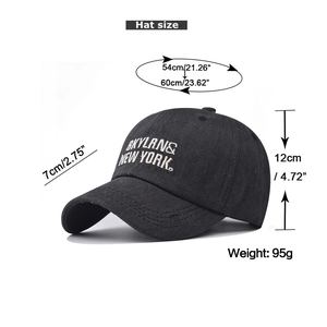 Detail of white BKYLANS NEW YORK embroidery on washed black cotton baseball cap