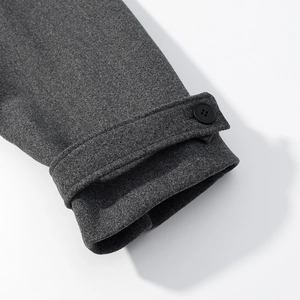 Detail of dark gray wool coat cuff featuring decorative strap and black button