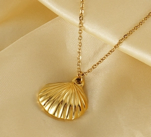 Detailed close-up of a 18K gold fan-shaped pendant on silk fabric background