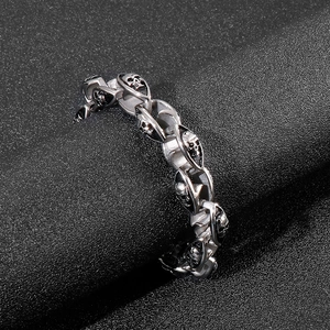 Detailed view of heavy silver double skull curb chain bracelet for men on a black texture