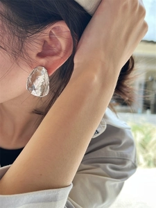 Close-up of 925 silver stud earrings with abstract irregular texture on model