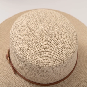 Macro detail of beige paper straw hat weaving with brown leather strap ornament