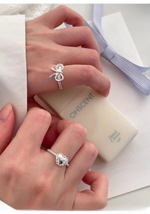 Detail of s925 silver bow and heart rings worn by a model in a sweet minimalist style