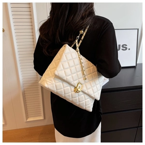 Close-up of white quilted leather texture with gold metal chain and rotary lock