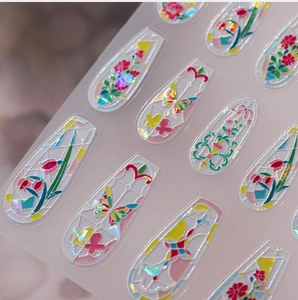 Détail macro de stickers ongles holographiques floraux avec dorures et texture 3D