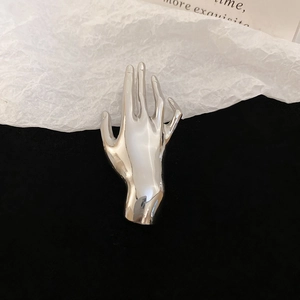 Detail view of glossy silver palm brooch with high polished finish and creative hand design