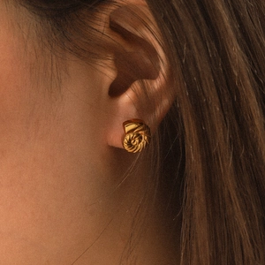 Macro detail of a vintage 18K gold plated stainless steel spiral seashell stud earring