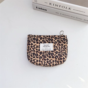 Close-up of leopard print canvas mini makeup pouch with metal zipper on a white desk