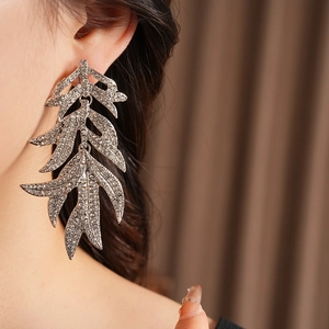 Close-up of sparkling rhinestone leaf tassel earrings in silver finish on a model