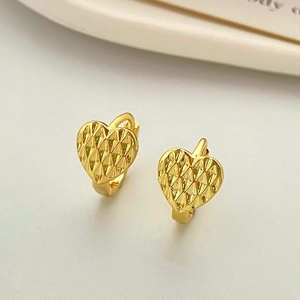 Close-up of golden heart-shaped hoop earrings with diamond-cut geometric texture