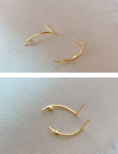 Close-up of minimalist gold curved ear studs featuring a delicate zircon stone inlay