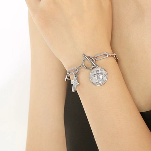 Detail of silver OT buckle bracelet featuring cross and religious relief charms