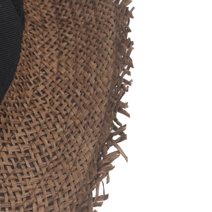 Detail view of dark brown straw sun hat with breathable woven texture and fringed edge