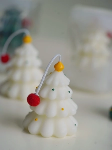 Macro view of mini Christmas tree candle with colorful polka dots and red pom-pom top