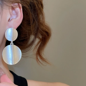 Close-up of minimalist matte silver brushed double disc pendant earrings on model