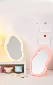 Detail of pink and beige cloud-shaped vanity mirrors on a decorative wooden shelf
