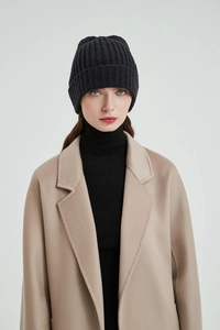 Close-up of a black knit beanie paired with a light camel cashmere coat for autumn