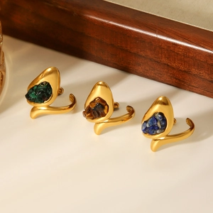 Detailed view of three gold rings with inlaid green, blue, and brown natural stones