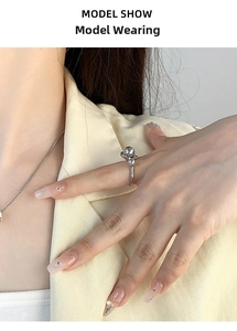 Detail shot of a silver adjustable ring featuring a large grey pearl and a small white pearl