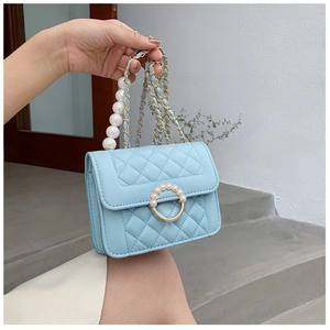 Detail of light blue quilted crossbody bag with pearl handle and golden chain strap