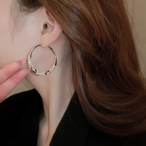 Macro detail of twisted silver hoop earrings with sparkling diamond pavé for women