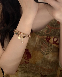 Close-up of double-layered baroque pearl bracelet with gold coin charm on female wrist