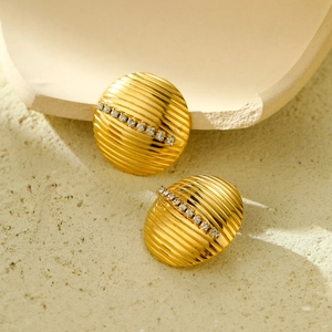 Gros plan de boucles d'oreilles dorées en titane avec textures et strass brillants