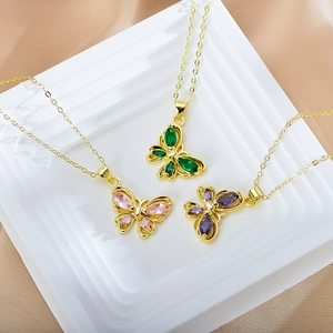 Detailed shot of three gold butterfly necklaces with green, pink, and blue gemstones