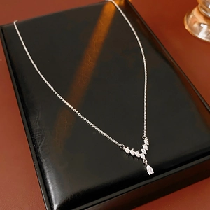 Detail of silver V-shaped necklace with teardrop cubic zirconia on black leather display