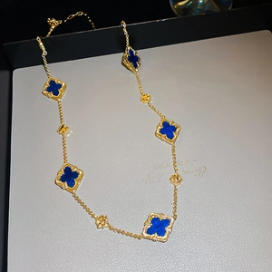 Detailed view of the gold-plated chain featuring blue clover charms and floral accents