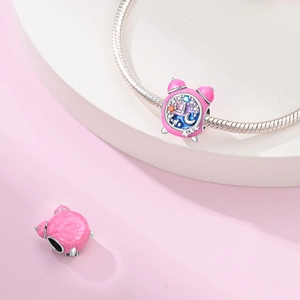 Macro shot of pink alarm clock charm with moon, stars, and colorful cubic zirconia