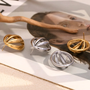 Artistic close-up of gold and silver hollow sphere stud earrings on a wooden branch