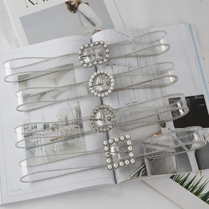 Detailed flat lay of transparent PVC belts with pearl and rhinestone buckle designs