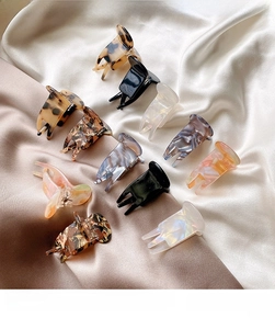 Detailed flat lay of acetate hair claw clips set in various colors on silk fabric