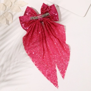Close-up of rose red sequin oversized bow hair clip with long ribbons and metal spring clip