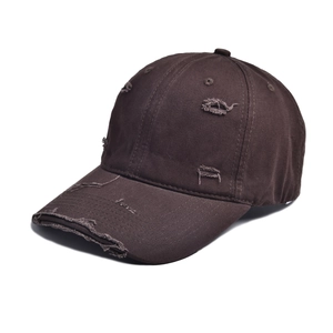 Close-up of distressed cotton twill fabric and torn details on a dark brown baseball cap