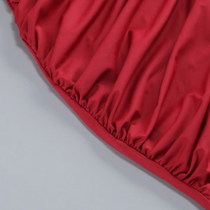 Detailed macro view of the ruched texture and pleated red knit fabric on a slim dress