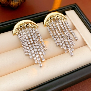 Detailed close-up of golden moon earrings with sparkling rhinestone fringe on a cushion