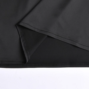 Gros plan de l'ourlet de la robe noire montrant le tissu lisse et les coutures de qualité