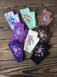 Flat lay of knit fingerless gloves in various colors with floral embroidery detail