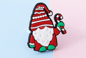 Nahaufnahme eines Weihnachtsgnom-PVC-Schuhanhängers mit Zuckerstange auf Pastellgrund