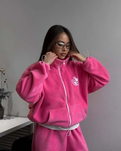 Détail de la veste polaire rose fuchsia avec col montant, zip et texture douce au toucher