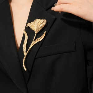 Detailed view of a golden tulip flower brooch pinned on a black suit lapel