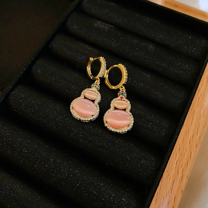 Detailed macro view of gold-plated pink cat-eye stone gourd earring on black velvet box