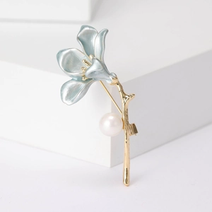 Detail of light blue enamel flower brooch with gold stem and elegant white pearl accent