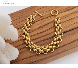 Detail view of gold chunky chain bracelet with OT toggle closure on dark wood tray