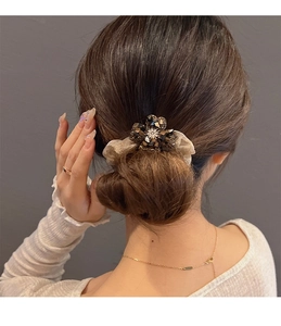 Close-up of sparkling rhinestone clover scrunchie worn on a bun hairstyle for women