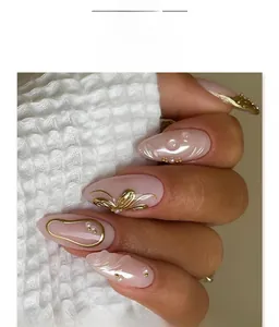 Close-up of French gold almond press-on nails with 3D pearls and relief patterns