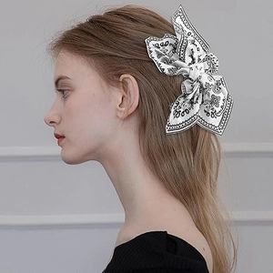 Elegant white bow hair claw clip with black paisley print worn by a female model
