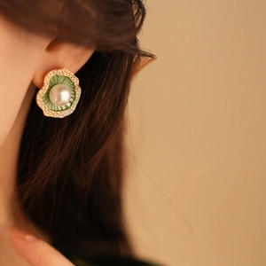 Gros plan d'une boucle d'oreille perle avec texture verte et bordure dorée